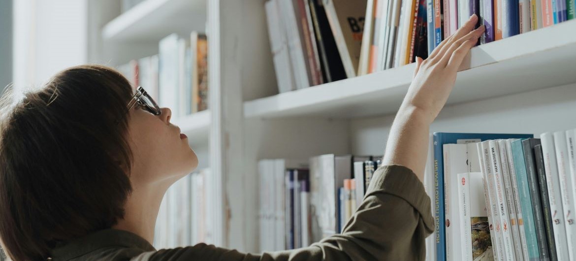 A person looking at books on a bookshelf.