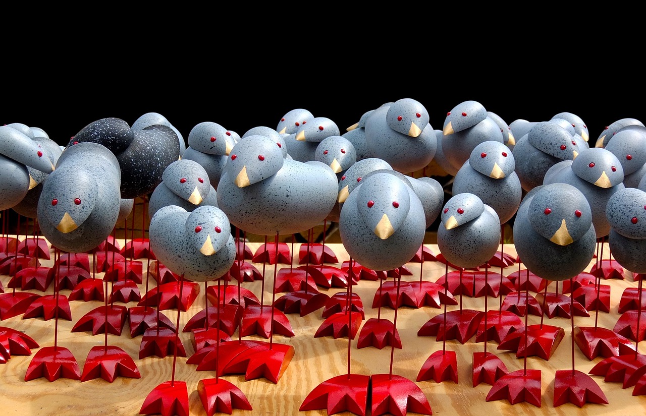 A collection of funny-looking wooden bird statues. Each statue is crafted with googly eyes, a wooden egg for the body, large wooden feet, and skinny metal rods for legs.