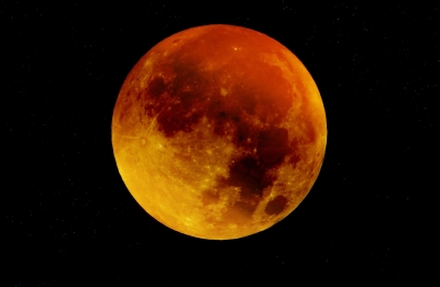 Photograph of a lunar eclipse with the moon appearing orange and yellow.