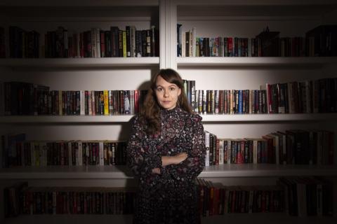 A woman standing in front of a wall of bookshelves.