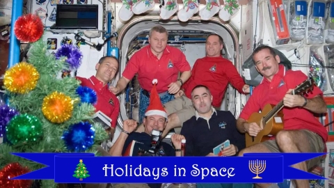 A group of astronauts on the International Space Station pose for a holiday photo near an improvised Christmas tree.