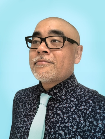 A bald Asian man with a razor stubble beard and mustache is wearing glasses. A photo of Dan Santat.