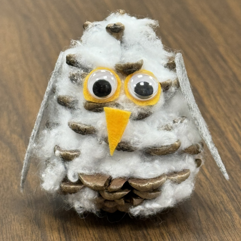 A picture of a snowy owl made out of a pinecone.