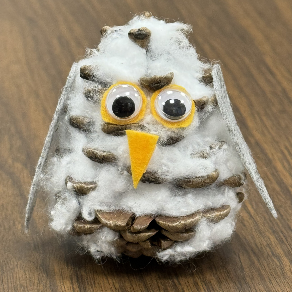 A picture of a snowy owl made out of a pinecone.