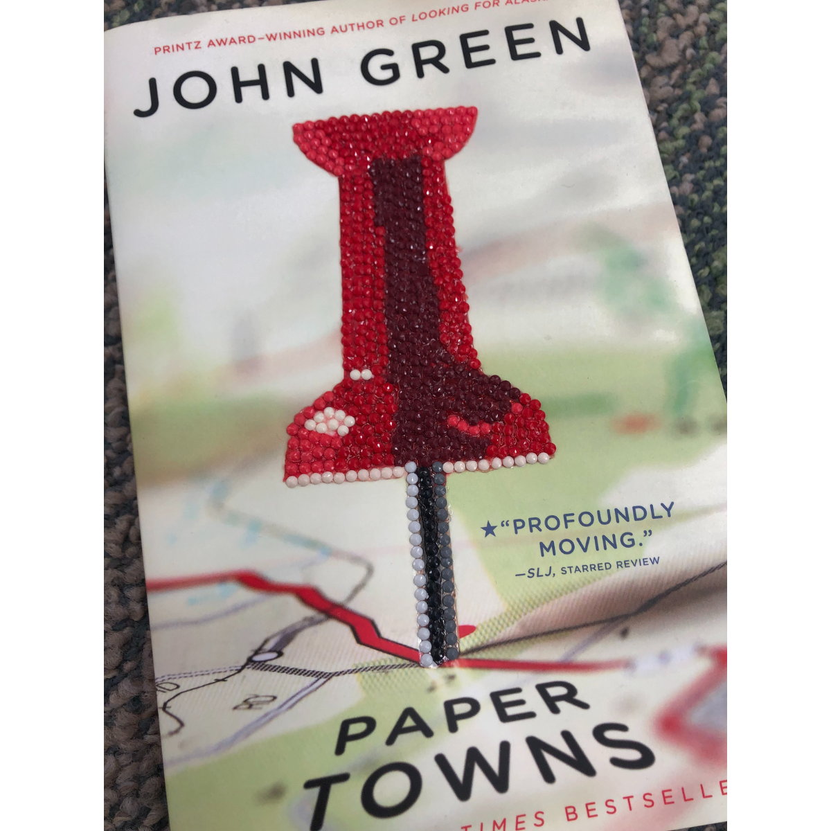 A picture of John Green's Paper Towns with the push pin bedazzled.