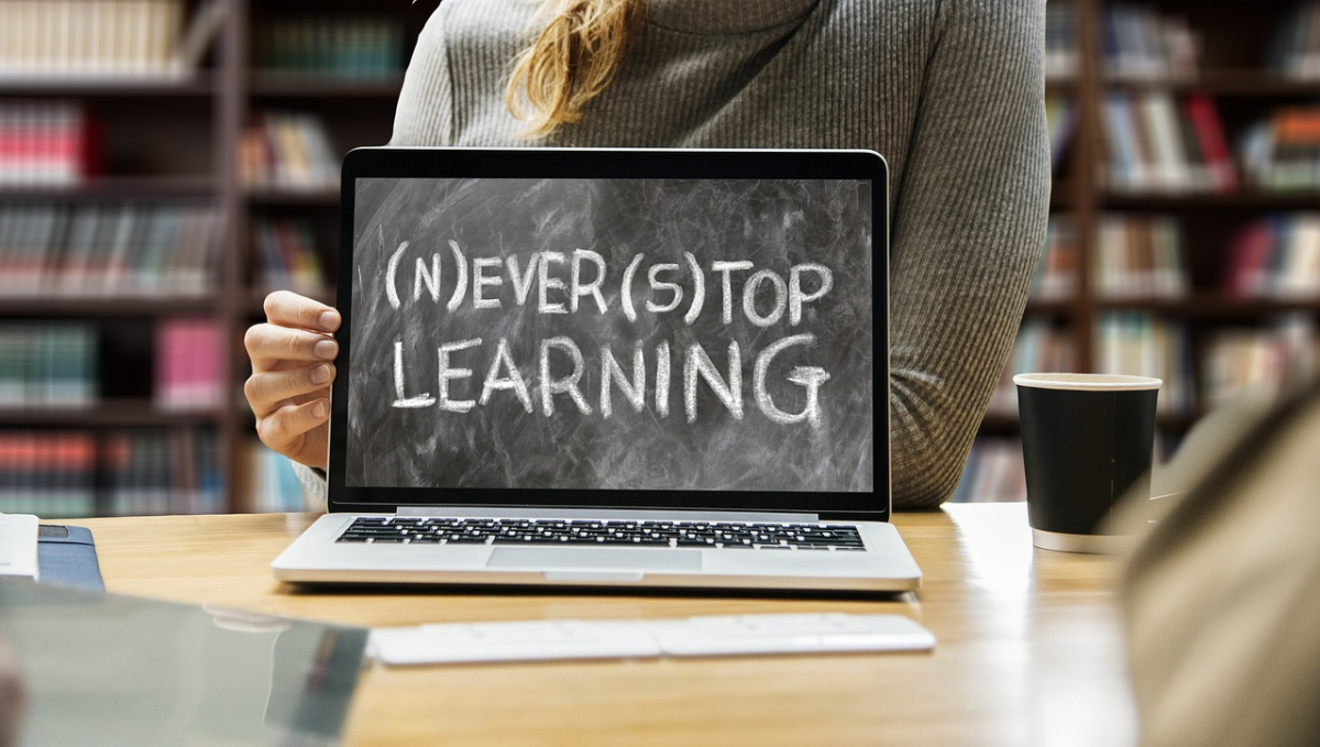 An open laptop with "Never Stop Learning" displayed on the screen.